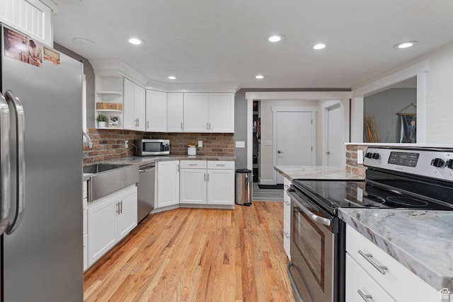 kitchen with light wood finished floors, open shelves, white cabinets, and stainless steel appliances