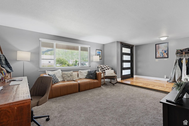carpeted office with baseboards and a textured ceiling