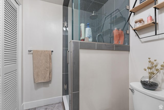 full bathroom with baseboards, toilet, a stall shower, and a closet