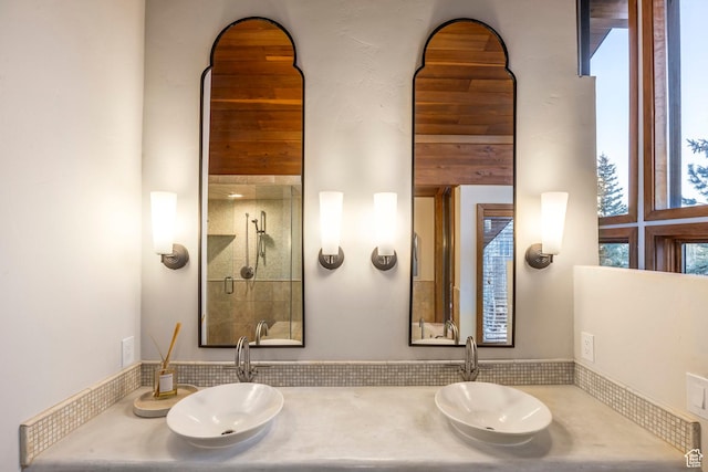 full bathroom featuring double vanity, a sink, and a tile shower