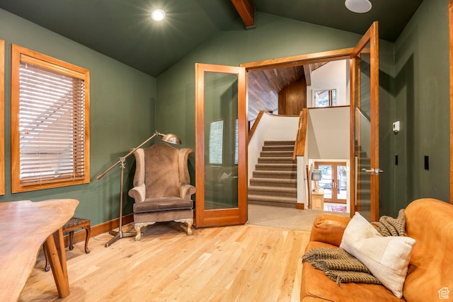 sitting room with baseboards, stairs, wood finished floors, a healthy amount of sunlight, and vaulted ceiling with beams