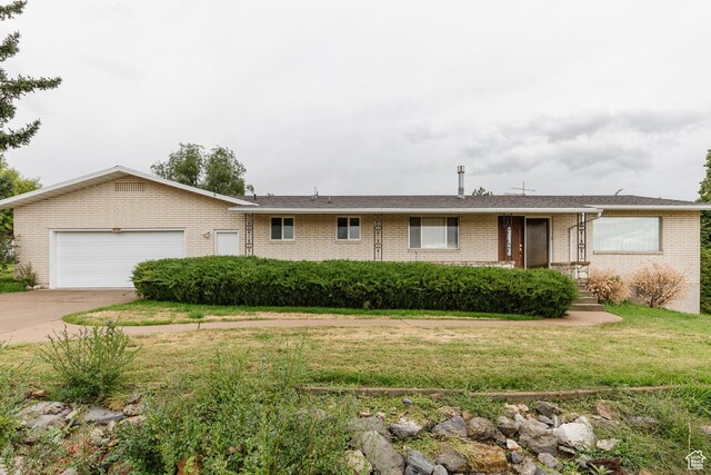single story home featuring a front yard, a garage, brick siding, and concrete driveway