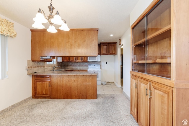 kitchen with white appliances, backsplash, a sink, and a chandelier