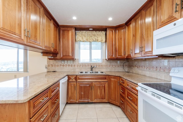 kitchen featuring white appliances, light stone countertops, brown cabinets, a sink, and light tile patterned floors