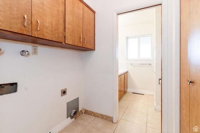 laundry room with hookup for an electric dryer, light tile patterned floors, baseboards, visible vents, and cabinet space