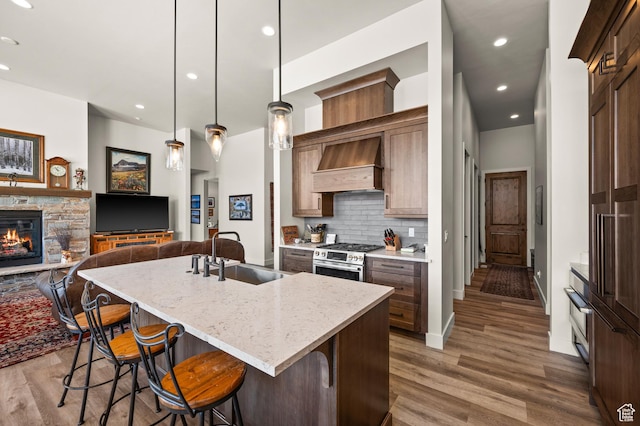481 Thorn View Ct Unit 6, Kamas, UT 84036 - kitchen featuring a sink, a breakfast bar area, stainless steel gas range oven, custom range hood, and decorative backsplash