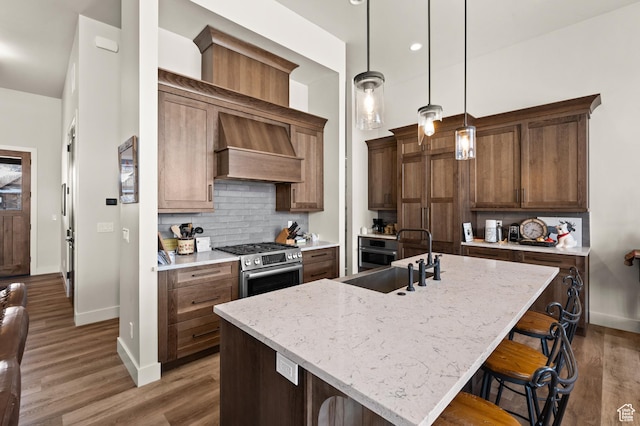 481 Thorn View Ct Unit 6, Kamas, UT 84036 - kitchen with decorative backsplash, custom exhaust hood, stainless steel range with gas cooktop, a sink, and a kitchen breakfast bar