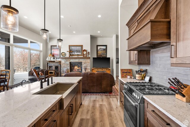 481 Thorn View Ct Unit 6, Kamas, UT 84036 - kitchen with premium range hood, stainless steel range with gas cooktop, a sink, light wood-type flooring, and backsplash