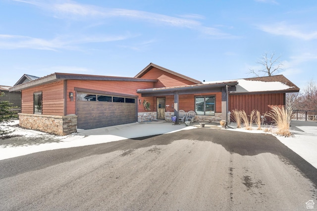 mid-century modern home with stone siding, aphalt driveway, and an attached garage