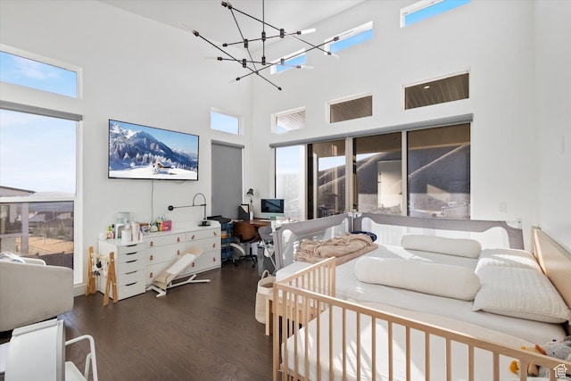 bedroom featuring a high ceiling, wood finished floors, and a notable chandelier