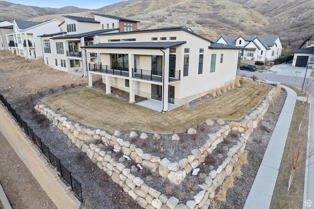 exterior space with stucco siding, fence, a residential view, a balcony, and a mountain view