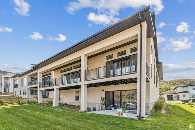 5641 N Canyon Rim Rd, Lehi, UT 84043 - rear view of house with stucco siding, a balcony, and a yard