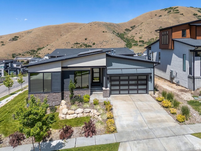 5641 N Canyon Rim Rd, Lehi, UT 84043 - modern home with a mountain view, stone siding, a garage, roof mounted solar panels, and concrete driveway