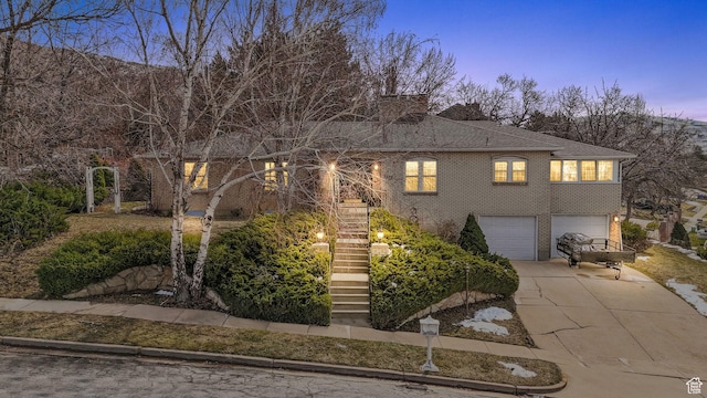view of front of property featuring concrete driveway, stairway, an attached garage, brick siding, and a chimney