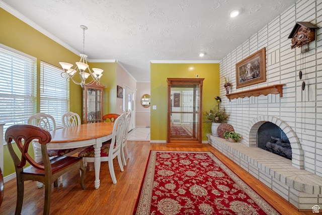 1376 Granada Dr, Bountiful, UT 84010 - dining space featuring ornamental molding, a textured ceiling, light wood-style flooring, a notable chandelier, and a fireplace