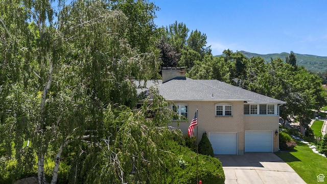 1376 Granada Dr, Bountiful, UT 84010 - view of front of home featuring brick siding, a garage, driveway, and a chimney