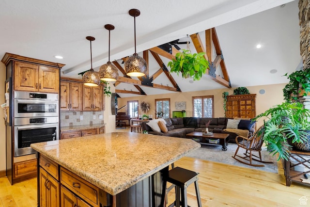 1603 E Millbrook Way, Bountiful, UT 84010 - kitchen with double oven, a center island, light wood finished floors, brown cabinetry, and light stone counters