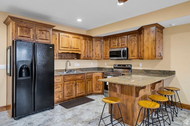 1603 E Millbrook Way, Bountiful, UT 84010 - kitchen featuring stainless steel appliances, a peninsula, a breakfast bar area, brown cabinetry, and dark stone counters