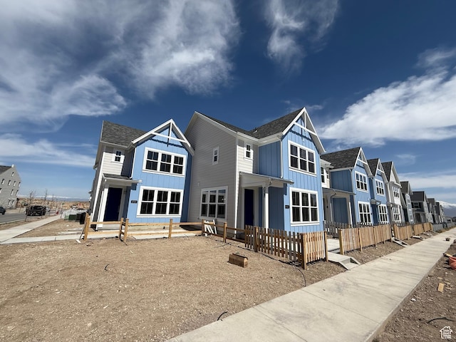 back of property featuring a residential view, board and batten siding, and fence