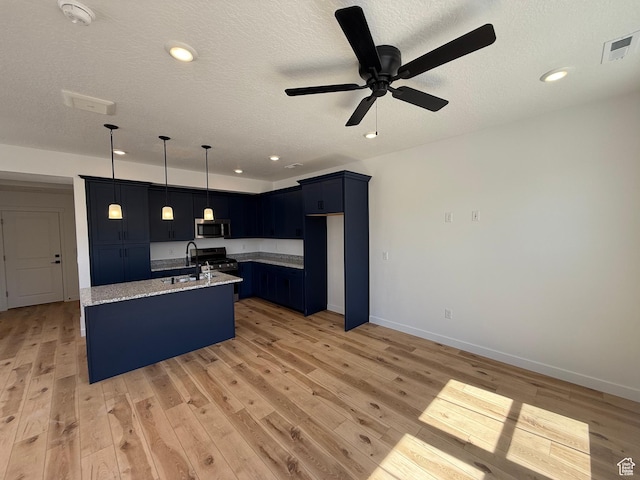 kitchen with visible vents, a ceiling fan, a center island with sink, light stone counters, and stainless steel appliances