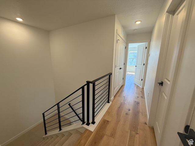 hallway with baseboards, an upstairs landing, recessed lighting, and light wood finished floors