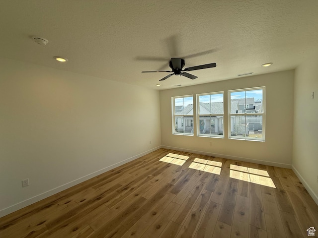 unfurnished room with visible vents, baseboards, a ceiling fan, a textured ceiling, and wood finished floors