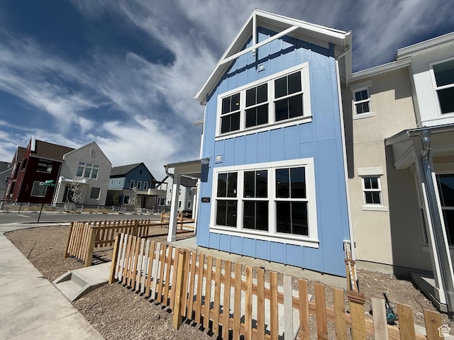 view of property exterior featuring a residential view, board and batten siding, and fence