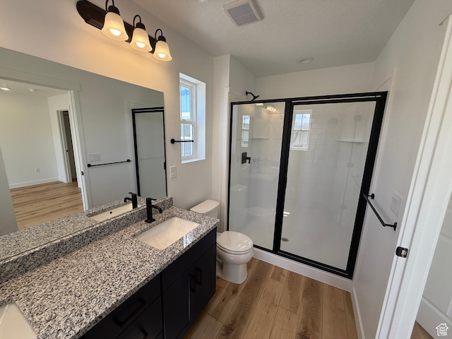 bathroom with vanity, a stall shower, toilet, visible vents, and wood finished floors