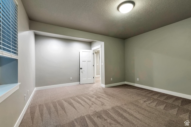 3240 W Oxford Loop Unit 219, Mountain Green, UT 84050 - spare room with baseboards, carpet flooring, and a textured ceiling