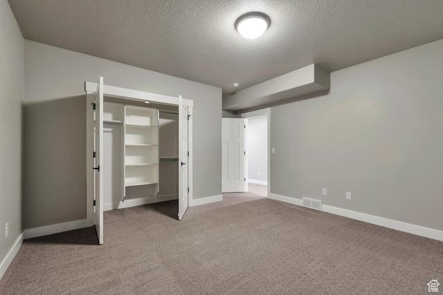 3240 W Oxford Loop Unit 219, Mountain Green, UT 84050 - unfurnished bedroom with a closet, carpet flooring, a textured ceiling, visible vents, and baseboards