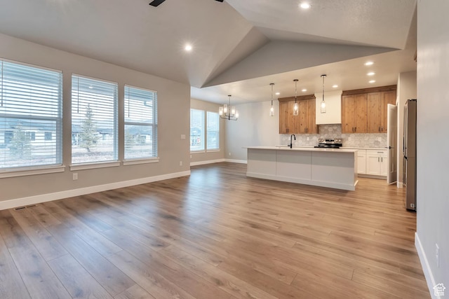 3240 W Oxford Loop Unit 219, Mountain Green, UT 84050 - kitchen with open floor plan, tasteful backsplash, light wood-type flooring, stainless steel appliances, and ceiling fan with notable chandelier