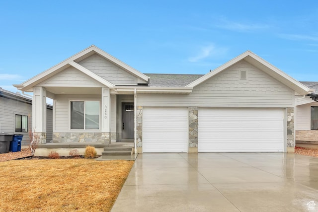 view of front of house with stone siding, concrete driveway, a shingled roof, and an attached garage