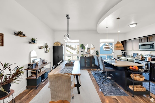 interior space with stainless steel microwave, light countertops, electric range, a breakfast bar area, and wood finished floors