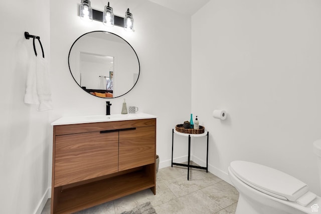 bathroom with toilet, vanity, and baseboards