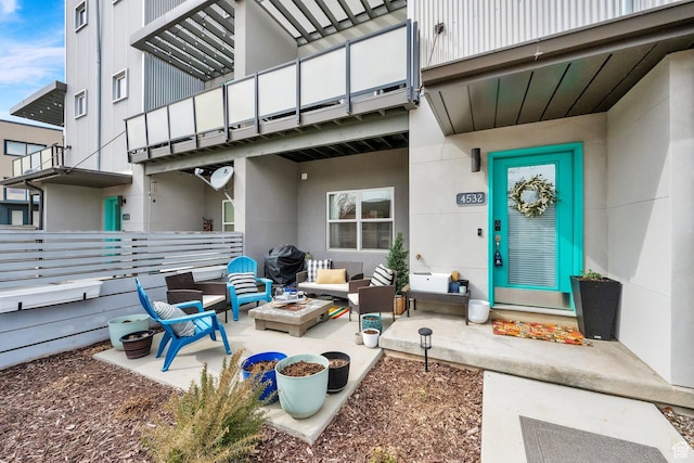 property entrance featuring a patio, a balcony, stucco siding, and an outdoor hangout area