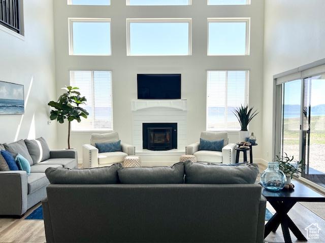 650 Blue Sage Dr, Fish Haven, ID 83287 - living room featuring light wood-style floors, a towering ceiling, a glass covered fireplace, and a healthy amount of sunlight