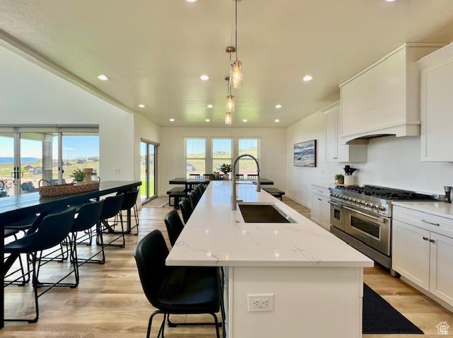 650 Blue Sage Dr, Fish Haven, ID 83287 - kitchen featuring range with two ovens, a sink, white cabinetry, light wood-type flooring, and a kitchen island with sink