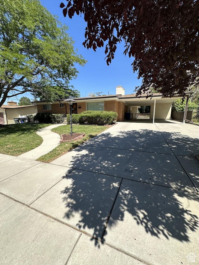 ranch-style house featuring a front yard, an attached carport, and concrete driveway
