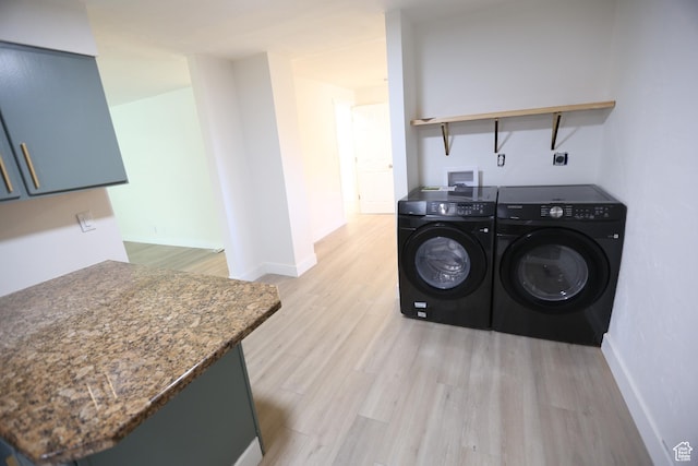 clothes washing area featuring laundry area, washing machine and dryer, baseboards, and light wood finished floors