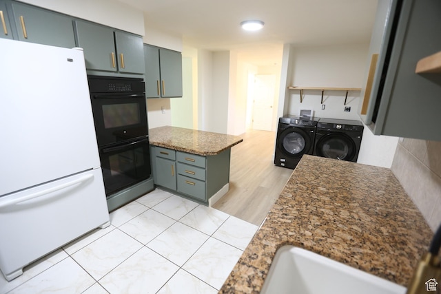 kitchen with washer and clothes dryer, a sink, freestanding refrigerator, dobule oven black, and a peninsula