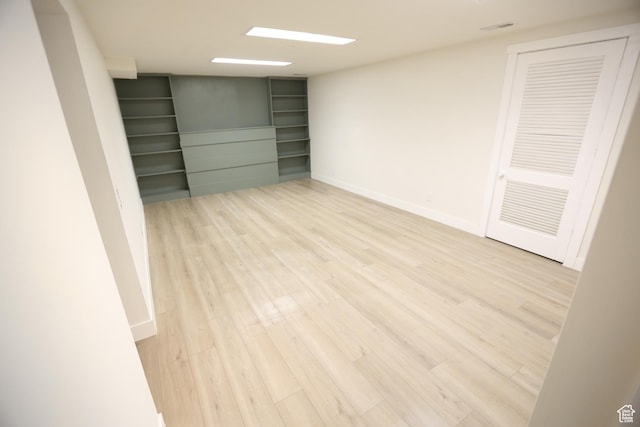 spare room with baseboards, light wood-style floors, and visible vents