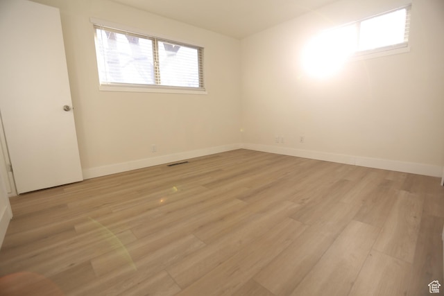 unfurnished room featuring baseboards, light wood-style floors, and visible vents