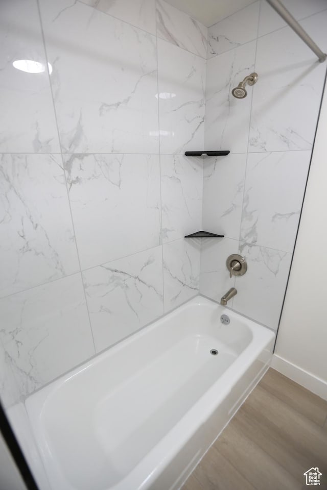 full bathroom featuring baseboards, wood finished floors, and shower / bathtub combination