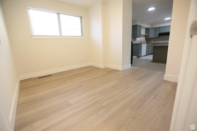 spare room with recessed lighting, light wood-type flooring, baseboards, a sink, and visible vents
