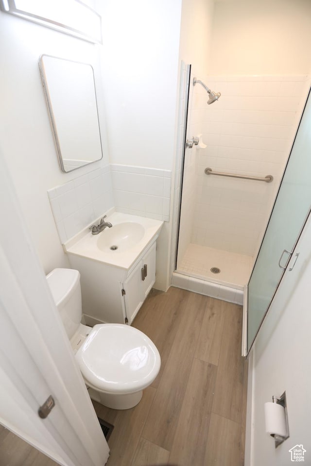 bathroom with a stall shower, toilet, wood finished floors, and vanity