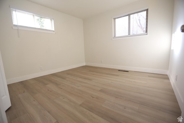 spare room featuring baseboards, visible vents, and light wood-type flooring