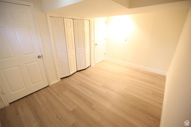 unfurnished bedroom featuring baseboards, a closet, and light wood-style floors