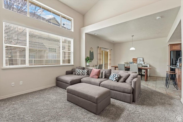 living room with baseboards, light tile patterned floors, and light colored carpet