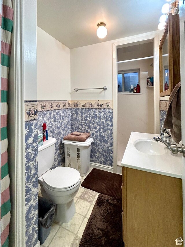 full bathroom featuring a wainscoted wall, curtained shower, toilet, and vanity