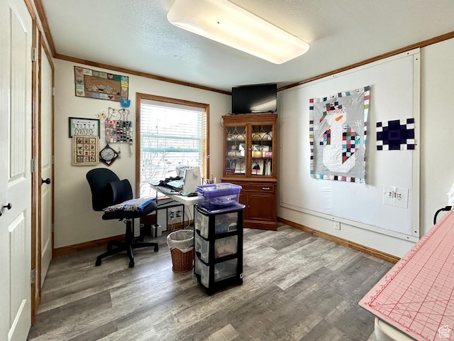 office area featuring baseboards, a textured ceiling, ornamental molding, and light wood finished floors